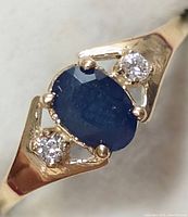 Top-front view of ring showing oval blue sapphire and two round diamonds