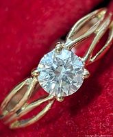 Front view of ring showing round brilliant cut diamond and split shank design on red background