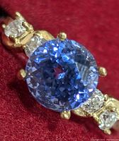 Close-up front view of round tanzanite center with flanking diamonds