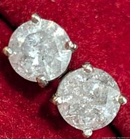 Two round diamond studs in four-prong settings on red velvet background