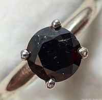 Close-up top view of faceted round black diamond highlighting facets and surface inclusions