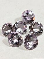 Close-up of five round faceted amethyst gemstones showing their light purple color and cut.