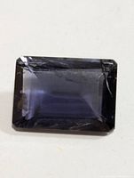 Top view of rectangular faceted iolite gemstone showing deep bluish-violet color and clarity.