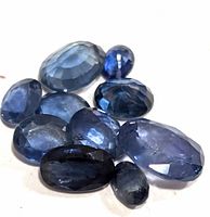 Cluster of ten faceted blue sapphire gemstones, showing color and cut variety.