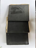 Three black stamp albums stacked, showing wear and age