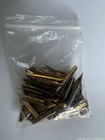 Plastic bag containing a collection of assorted metal fountain pen nibs of different shapes and sizes.