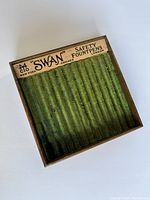 Top view of the vintage wooden display case showing the green felt interior and the Swan Safety Fountain Pens label with city names New York, Chicago, and London.