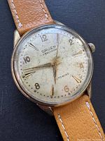 Close-up front view of the vintage Gruen Precision watch face showing aging and wear on dial and hands