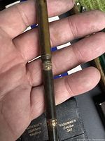 Photo of vintage Waterman fountain pen held in hand showing gold-colored bands and worn metal barrel with patina.