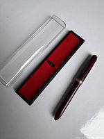 Vintage maroon Zephyr fountain pen in its box with red felt lining and clear plastic lid.