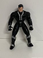 Front view of the David Xanatos action figure standing upright, showing his black suit with silver accents and detailed facial features including goatee.