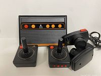 Front view of Atari Flashback 4 console with two wired joysticks and two paddle controllers arranged in front.