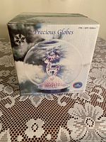 Original boxed Avon Precious Globes reindeer snow globe, front and side views of packaging showing winter scene and LED light feature.