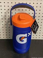 Front view of a blue and orange Gatorade Gx insulated jug with original tag hanging from the handle, showing the large Gx logo on the jug body.