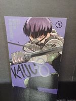 Front cover of Kaiju No. 8 Volume 4 manga showing main character Kafka Hibino in action pose holding sword, purple background.