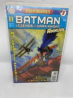 Front cover of Batman Legends of the Dark Knight Annual issue #1 showing Batman on a rooftop with old airplane in background and colorful sky.