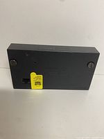 Photo of the front side of the PS2 Network Adapter showing the Ethernet port, screws, and caution label.