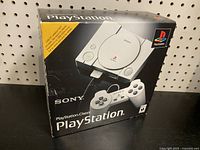 Front view of the PlayStation Classic box showing console and controller image with Sony and PlayStation logos.