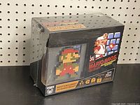 Front and side views of the sealed Super Mario Bros. Collector's Box showcasing the 8-bit Mario pixelated art and game-related graphics.