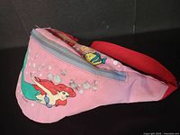 Side view of vintage pink Little Mermaid fanny pack with Ariel and Flounder graphics and red adjustable strap.
