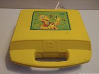 Bright yellow closed carrying case with Big Bird illustration and sturdy handle.