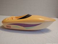 Side view of vintage Little Tikes yellow speedboat toy showing purple and green decals and black windshield.