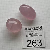 Two polished rose quartz stones on gridded background with measurement card.
