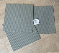 Three grey LEGO 48x48 base plates stacked, showing overall condition