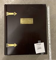 Top closed view of dark brown wooden memory box with brass hinges and plaque labeled, beside ruler for size reference.