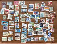 Top view of 66 assorted vintage used Canadian postage stamps arranged on a wooden surface.