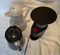 Photo of the Keurig coffee pot, Bodum coffee grinder, and white thermos pot on a fabric background showing the parts assembled.