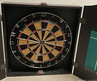 Open wooden cabinet with dartboard inside, showing the board and surrounding score tracking area.