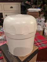 White plastic herb grinder viewed from side and top showing internal grinding spikes