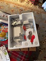 Apple peeler slicer with metal parts and red handles in styrofoam packaging