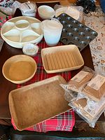 Overview of stoneware pans and plastic kitchen items arranged on table.