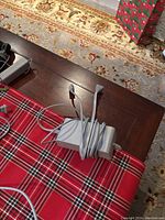 Wii console power adapter with cable on table with festive cloth and carpet floor background.