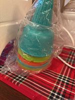 Stacked colorful reusable plastic cones wrapped in plastic alongside matching spoons.