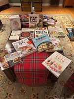Overview photo showing 13 keto cookbooks arranged around the Dash mini waffle maker box on a table with a plaid table runner.