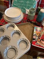 Overview of baking trays, ceramic butter bell and dishes on table with cookbooks.
