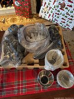 All manual food processor parts in cardboard packaging, wrapped in plastic and bubble wrap on a table with a Christmas plaid cloth.