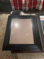 Decorative mirror with wide black matte frame, empty, on patterned floor