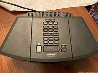 Top view showing numeric keypad, control buttons for CD, radio bands, and volume, with Bose branding.