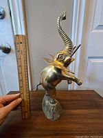 Full side view of large brass elephant statue with a ruler for size reference showing it approximately 8 inches tall.