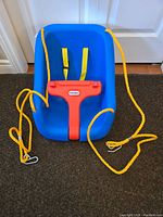 Blue Little Tikes swing seat with yellow hanging ropes, safety straps and red safety handle shown from front.