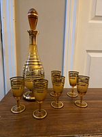 Full set showing decanter with stopper and six matching glasses arranged on table