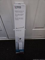 Box of Moen designer grab bar with integrated towel bar showing front side labeling and brand.