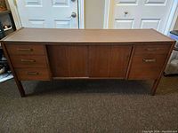 Front view of wooden parallel credenza buffet showing drawers and sliding doors.