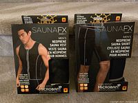 Front view of the two SAUNAFX products in original packaging; Men's Neoprene Sauna Vest and Sauna Short. Both marked Medium size and brand new.