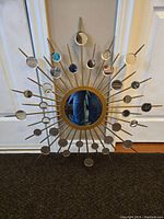 Front view of starburst mirror showing the circular central mirror with surrounding smaller round mirrors on radial rods in gold finish.