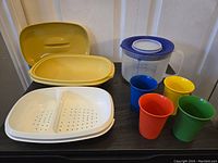 Full view of vegetable steamer parts, measuring cup, and four child size cups.